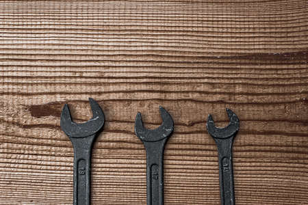 black steel wrench different sizes tool set layout on dark brown wood textured background with copy spaceの写真素材