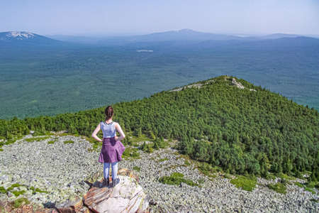 female in gray t-hirt and purple port jacket standing on top of mountain looking forward far to the mountain landscape. freedom travel conceptの写真素材