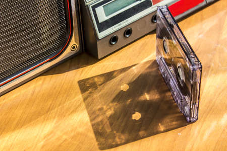 old vintage transparent tape audio cassette casts shadow on wood background. retro 80's 90's music conceptの写真素材