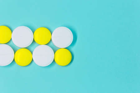 white and yellow round pills in a row on a blue background close-up layoutの写真素材