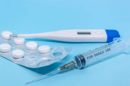 transparent syringe, white electronic thermometer and white tablets in a blister. medical examine and treatment conceptの写真素材