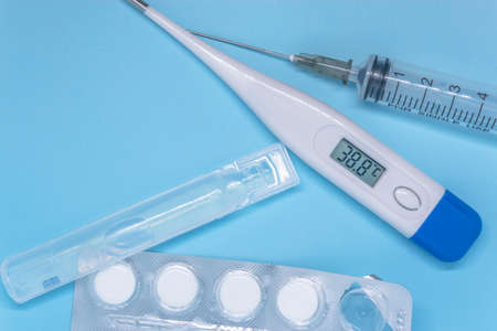 transparent syringe, white electronic thermometer and white tablets in a blister. medical examine and treatment conceptの写真素材