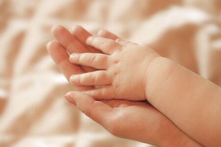 Small children's hand lies on a hand momの写真素材