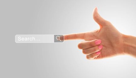 The index finger of a female hand points to the search fieldの写真素材