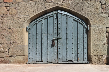 Stone wall with weathered obsolete antique wooden doorの写真素材