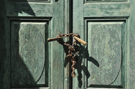 Old wooden green paint door with lock and chainの写真素材
