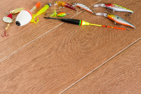 Frame fishing tackle - fishing spinning, hooks and lures on light wooden backgroundの写真素材