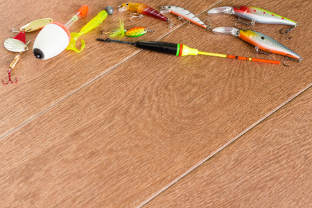 Frame fishing tackle - fishing spinning, hooks and lures on light wooden backgroundの写真素材