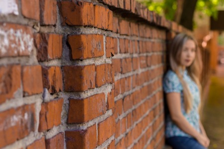 Blured girl standing near the red wall and waiting. Blured backgroundの写真素材