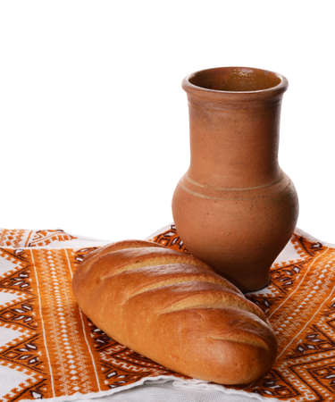 Antique wine pitcher with rustic loaf of bread isolated on whiteの写真素材