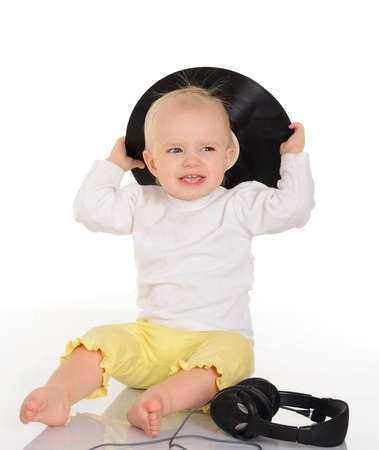 baby playing with old vinyl record and headphones on white backgroundの写真素材