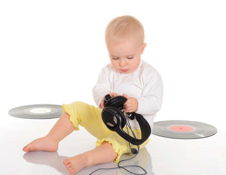 baby playing with old vinyl record and headphones on white backgroundの写真素材