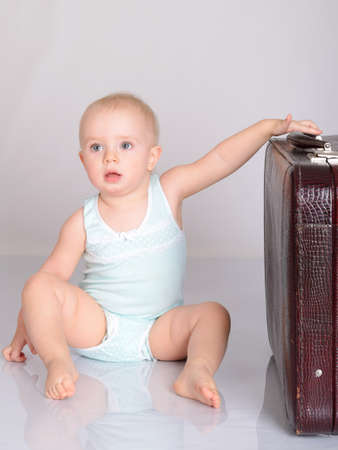 cute baby girl playing with suitcase on grey backgroundの写真素材