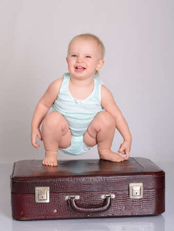 cute baby girl playing with suitcase on grey backgroundの写真素材