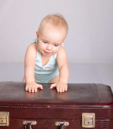cute baby girl playing with suitcase on grey backgroundの写真素材