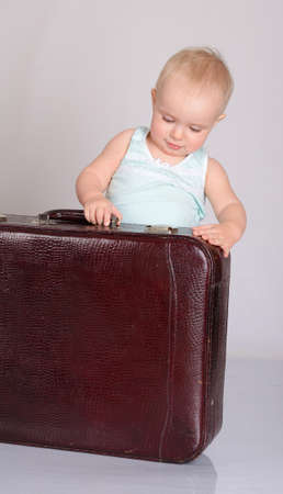 cute baby girl playing with suitcase on grey backgroundの写真素材