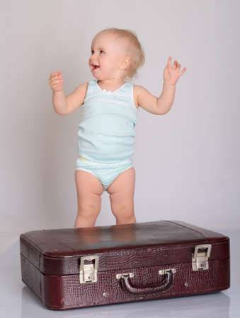 cute baby girl playing with suitcase on grey backgroundの写真素材