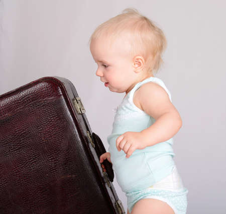 cute baby girl playing with suitcase on grey backgroundの写真素材