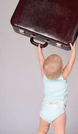 cute baby girl playing with suitcase on grey backgroundの写真素材