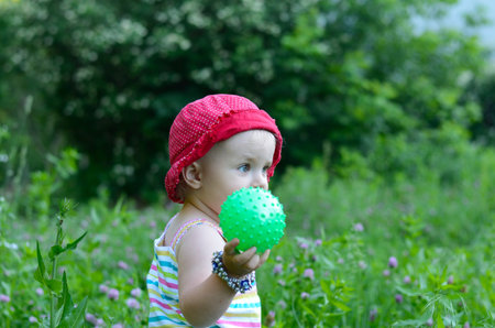 cute little girl sitting in the green fieldの写真素材