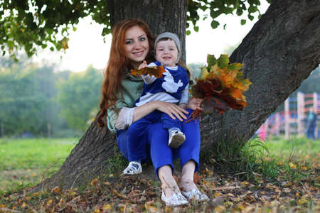 redhead girl with son Autumn leavesの写真素材