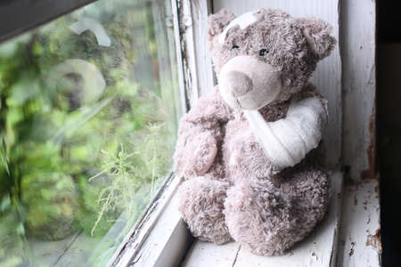 sick teddy bear sitting by the windowの写真素材