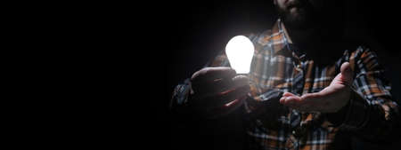 man in dark with glow bulb in a handの写真素材