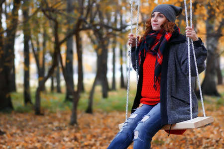 woman on swing in autumn parkの写真素材