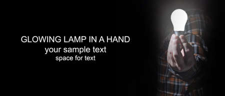 man in dark with glow bulb in a handの写真素材