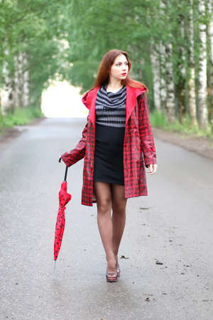 woman with umbrella red on street treeの写真素材