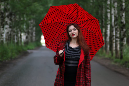 woman with umbrella red on street treeの写真素材