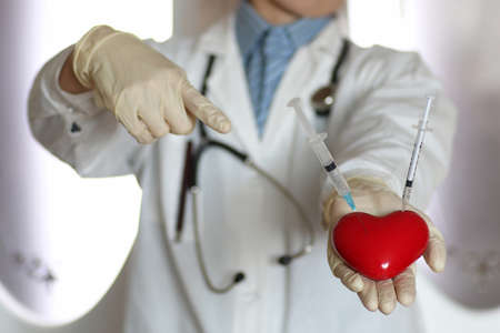 syringe in heart holding doctors hand conceptの写真素材