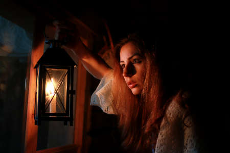 woman holding candle lamp in dark nightの写真素材