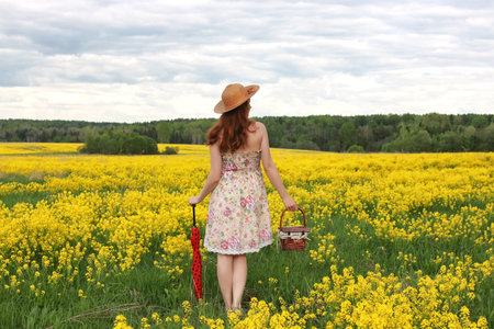 girl in a field of flowers with an umbrella and a hatの写真素材