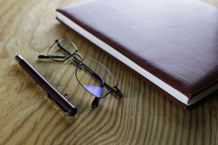 pen,  wallet, glasses and notebook on wooden tableの写真素材
