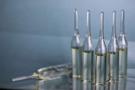 transparent vials of medicine on blue backgroundの写真素材