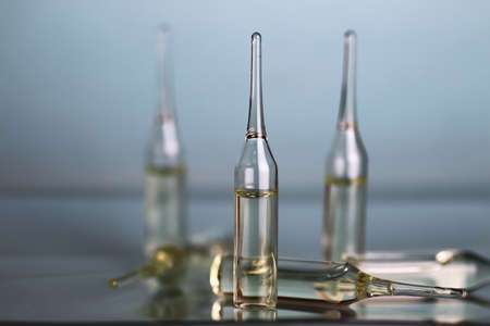 transparent vials of medicine on blue backgroundの写真素材