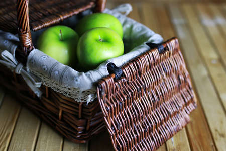 green apple in a basket on a wooden backgroundの写真素材