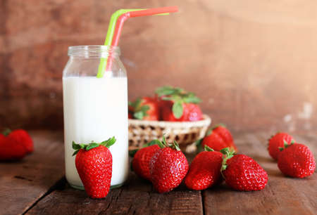 wooden table with strawberries and milk in a glassの写真素材