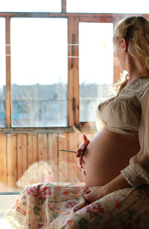 pretty pregnant woman sitting near the window
