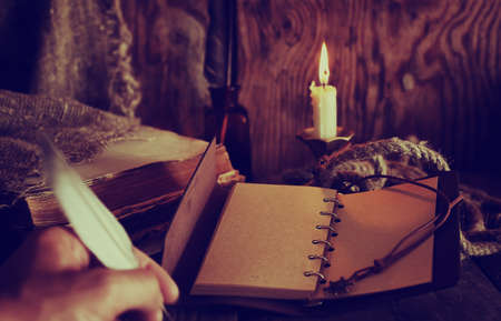 old retro styled composition of book candle and featherの写真素材