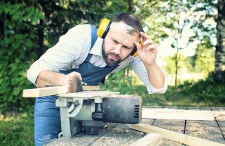 worker beard man with circular saw outdoor