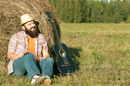 man with guitar and beer on the nature