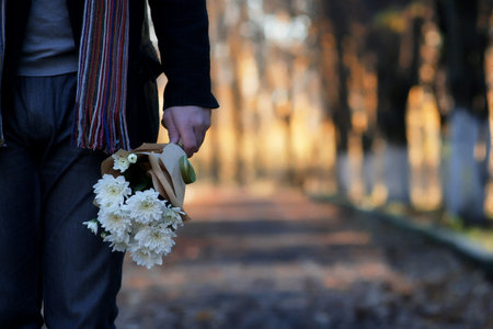 man waiting on a bench the date in autumn park with flower