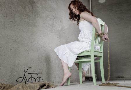 Portrait of a young red-haired girl on a background of gray plaster wallの写真素材