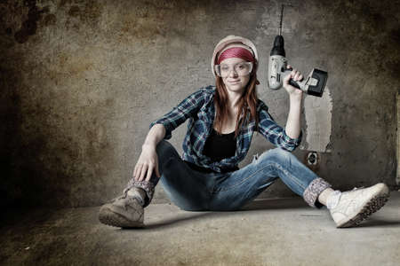 Portrait of a young red-haired girl on a background of gray plaster wallの写真素材