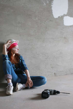 Portrait of a young red-haired girl on a background of gray plaster wallの写真素材