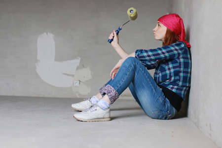 Portrait of a young red-haired girl on a background of gray plaster wallの写真素材