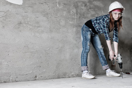 Portrait of a young red-haired girl on a background of gray plaster wallの写真素材