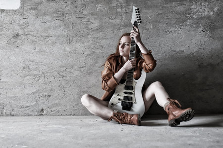 Portrait of a young red-haired girl on a background of gray plaster wall